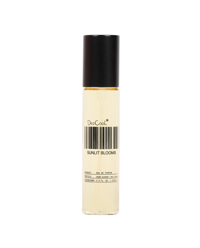 A clear cylindrical rollerball bottle with a black cap, containing a pale yellow liquid. The label reads 'DeeCool' and 'SUNLIT BLOOMS' with a barcode graphic, set against a plain white background.